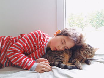 Girl with cat sleeping on bed at home