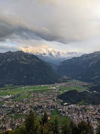 Aerial view of townscape by mountains against sky