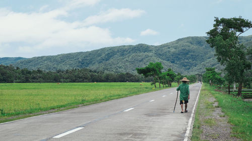 Rear view of man riding bicycle on road