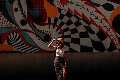 Full length of woman standing against graffiti wall