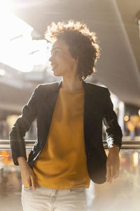 Businesswoman with hand in pocket leaning on railing