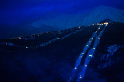 Aerial view of illuminated snowcapped mountains against sky at night
