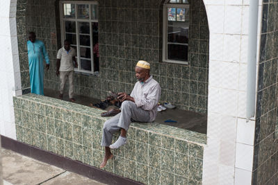 Full length of man sitting outside building