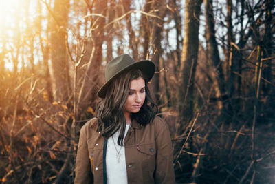 Portrait of woman standing by tree in forest