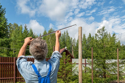 Rear view of man standing by tree against sky