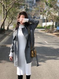 Woman covering face with hand while standing on road