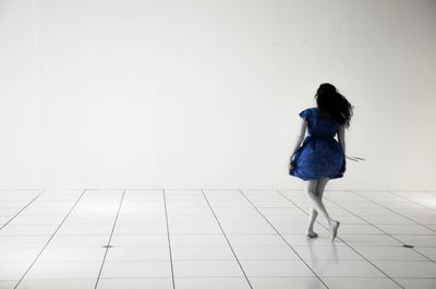 Rear view of woman standing on tiled floor