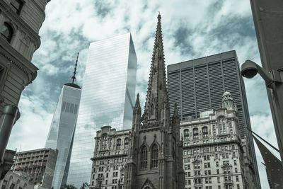 Low angle view of modern buildings against cloudy sky