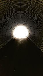 Low angle view of sunlight streaming through tunnel