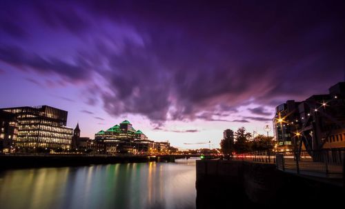 Illuminated buildings against cloudy sky at night