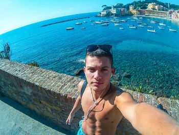 Portrait of man standing by retaining wall against sea