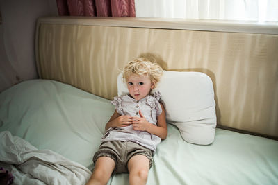 Young woman using mobile phone while lying on bed at home