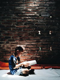 Full length of boy sitting on wall