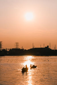 Silhouette boats in sea against sky during sunset