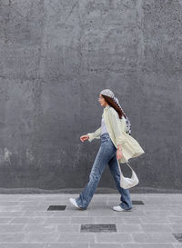 Full length of woman standing against wall