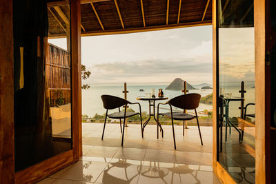 Empty chairs and tables in restaurant against sky