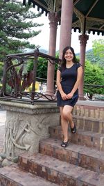 Portrait of smiling young woman against steps