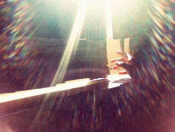 Close-up of hand on illuminated lighting equipment against sky