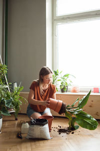 Woman sitting by potted plant on table