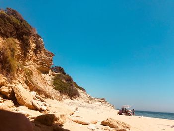 Rock formation on beach against clear blue sky