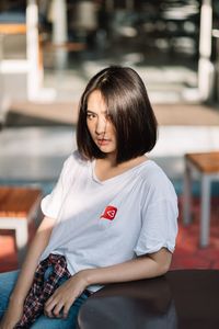 Portrait of beautiful young woman sitting in city