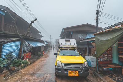 Vehicles on road amidst buildings against sky