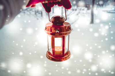 Holding in red glove red candle lantern in the winter forest. snow snowfall. christmas new year 