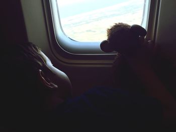Boy with toy sitting by airplane window