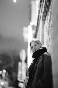 Side view portrait of young woman standing against wall