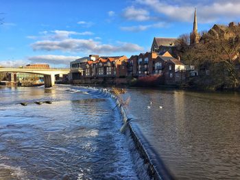 Scenic view of river against sky in city
