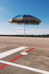 Parasol at airport runway against sky