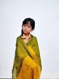 Portrait of young woman standing against white background