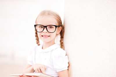Cute girl with tablet pc sitting against wall