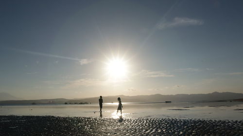 Silhouette people on beach against sky during sunset