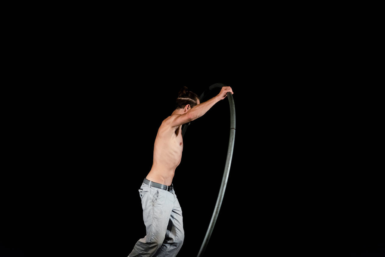 REAR VIEW OF MAN HOLDING UMBRELLA AGAINST BLACK BACKGROUND