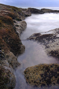 Scenic view of sea by rocks against sky