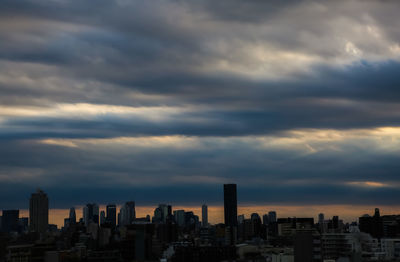 Modern buildings in city against sky during sunset