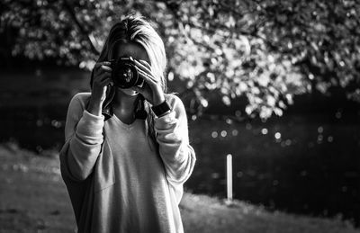 Woman photographing from camera at riverbank