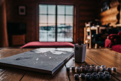 Painting by numbers on the wooden table in a mountain cabin with a window in the background. 