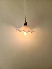 Low angle view of illuminated light bulb hanging on ceiling