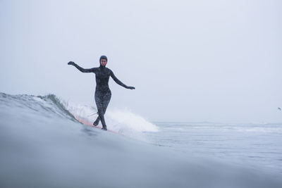 Full length of man surfing on sea against sky