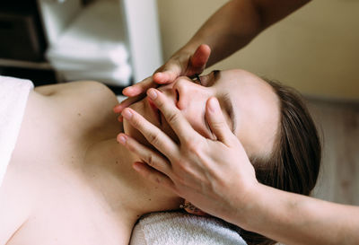 Cropped hand of massage therapist massaging woman face