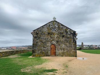 Old temple building on field against sky