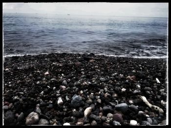 Close-up of pebbles on beach against sky