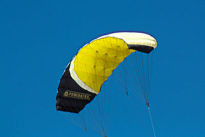 Low angle view of person paragliding against blue sky