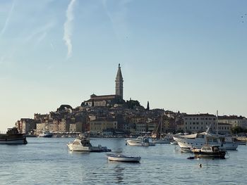 Boats in river by buildings against sky in city