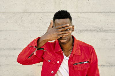 Portrait of young man standing against wall