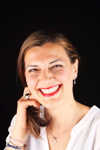 Portrait of smiling young woman against black background