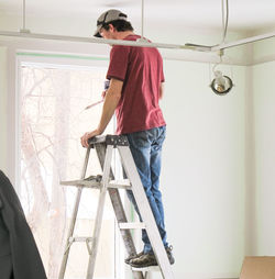 Full length of man standing on ladder while working at home