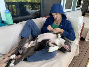 Full length of man with dog relaxing on bed at home